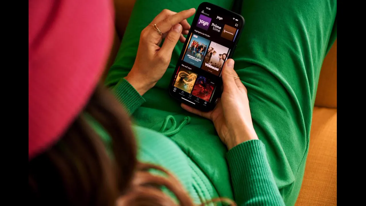 Hands holding a phone and scrolling through a streaming app's list of show titles